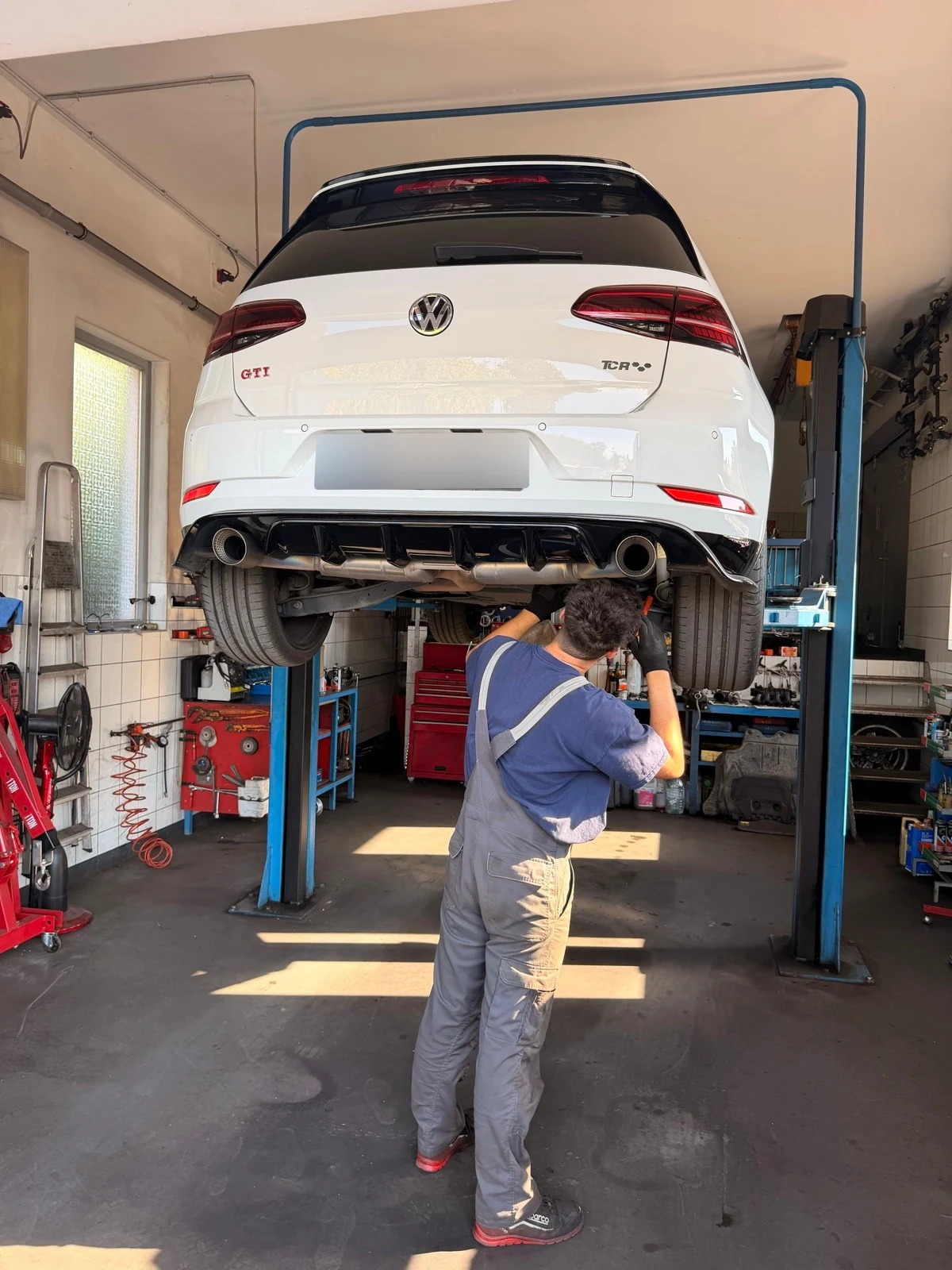 Munka egy emelőn álló Volkswagen Golf GTI hátsó futóművénél